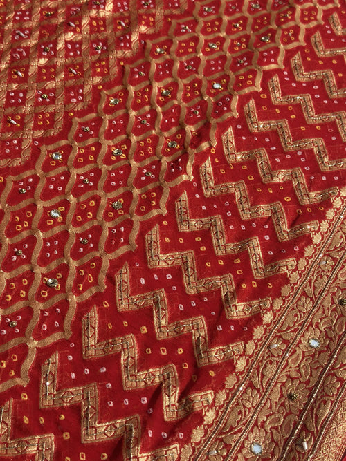 Close-up of hand-tied bandhej tie-dye and gold zari on red dupatta