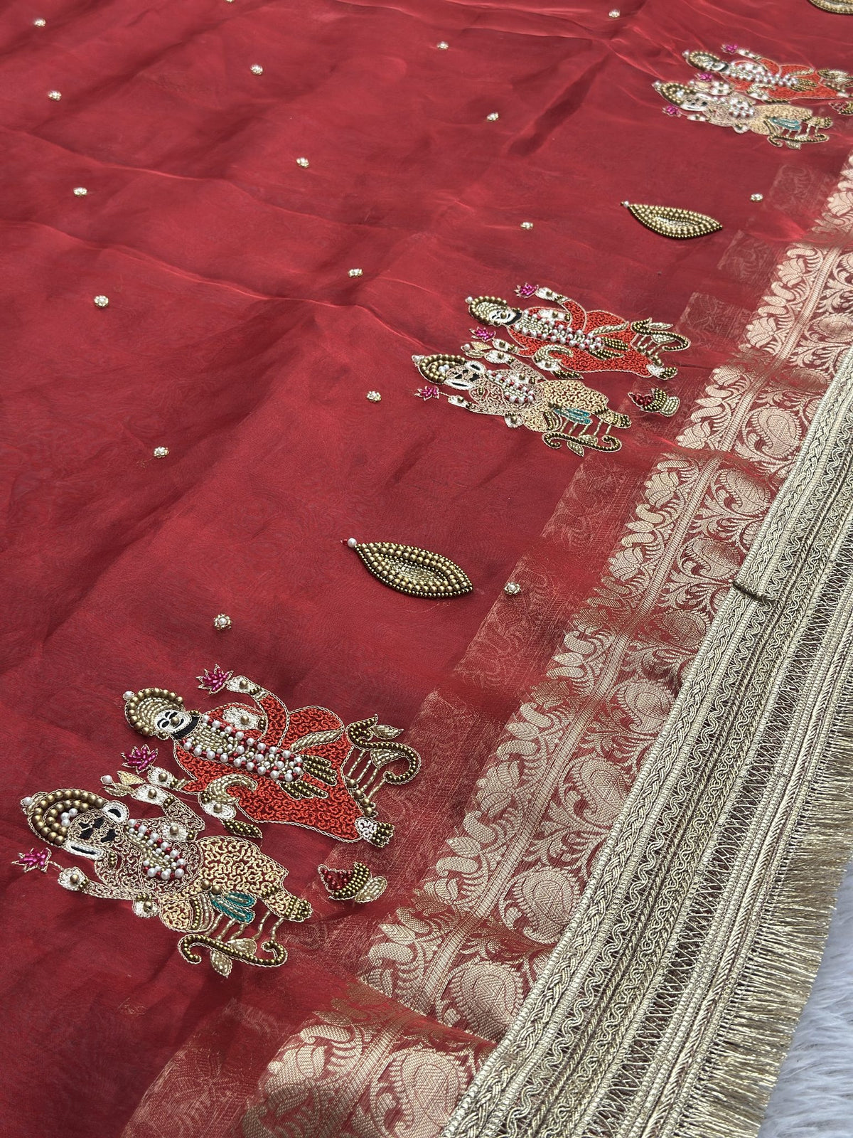 Close-up of embellished Ganesh and Laxmi motifs on red Banarasi saree