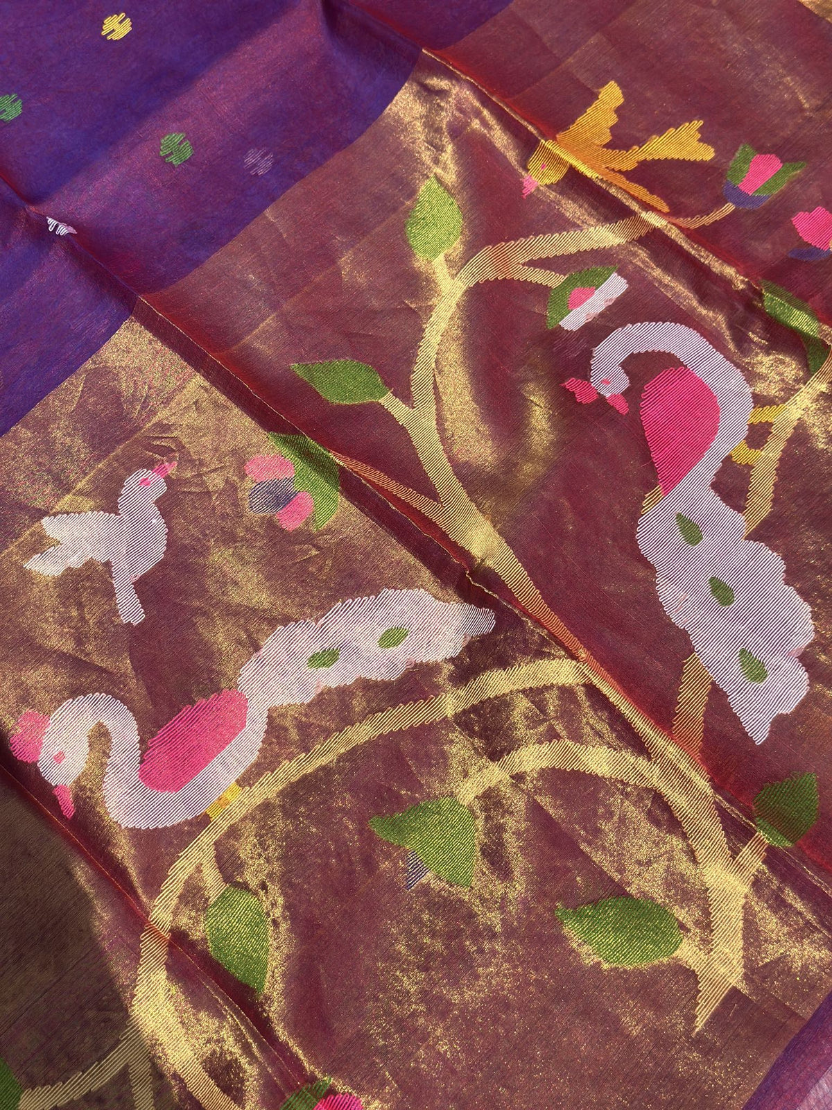 Close-up of woven peacock and floral vine motifs on burgundy purple Jamdani