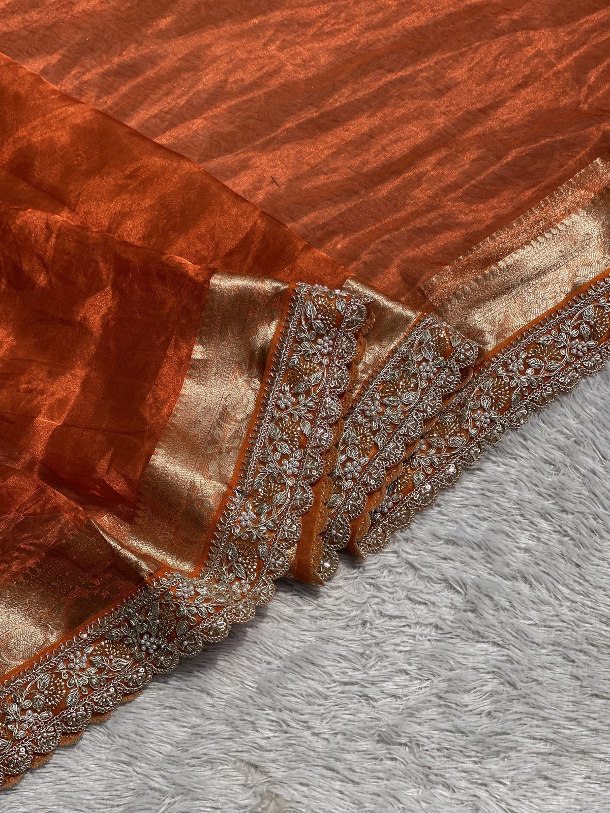 Close-up of embroidered scalloped border on orange Banarasi tissue saree